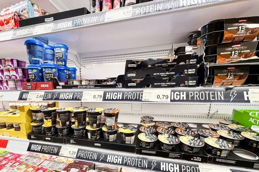 A range of high-protein items on display in the dairy aisle of a grocery store.